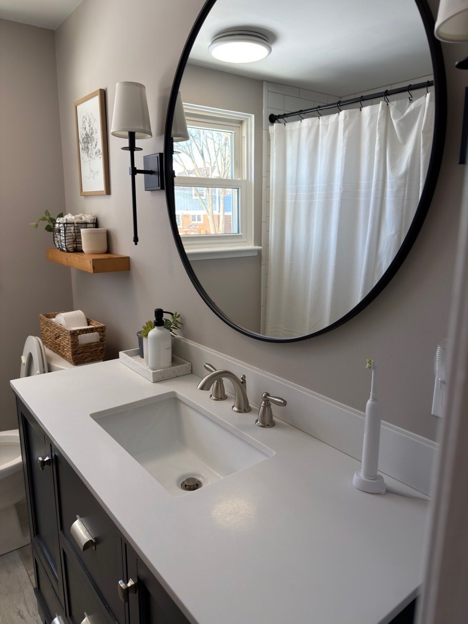 White countertop sink, black sink cabinet, round mirror deep cleaned